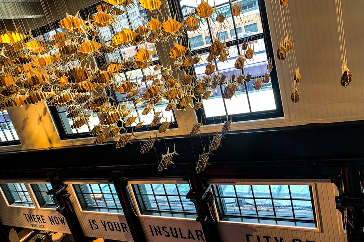the inside of a building with crafted fish hanging from the ceiling